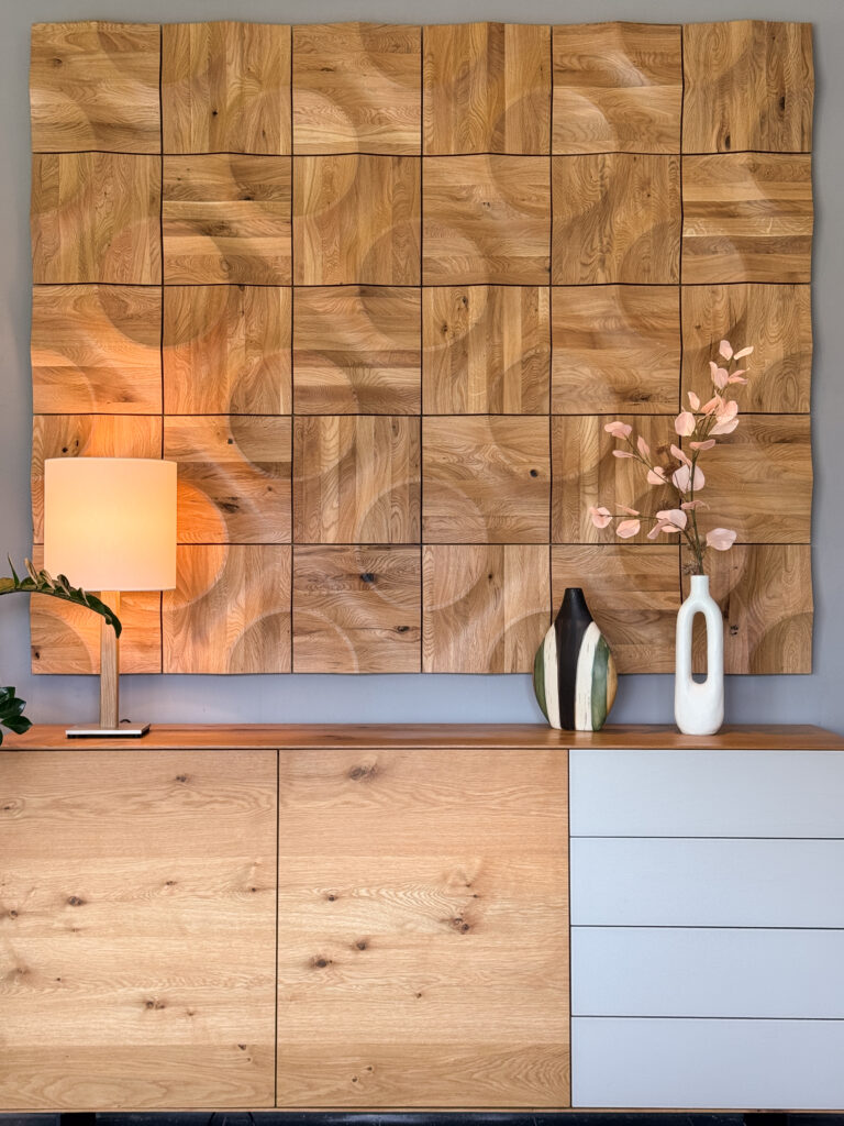 Moderne Kommode aus Holz mit Wanddeko aus strukturierten Holzplatten, dekoriert mit Designer-Vasen, Lampe und Zweigen